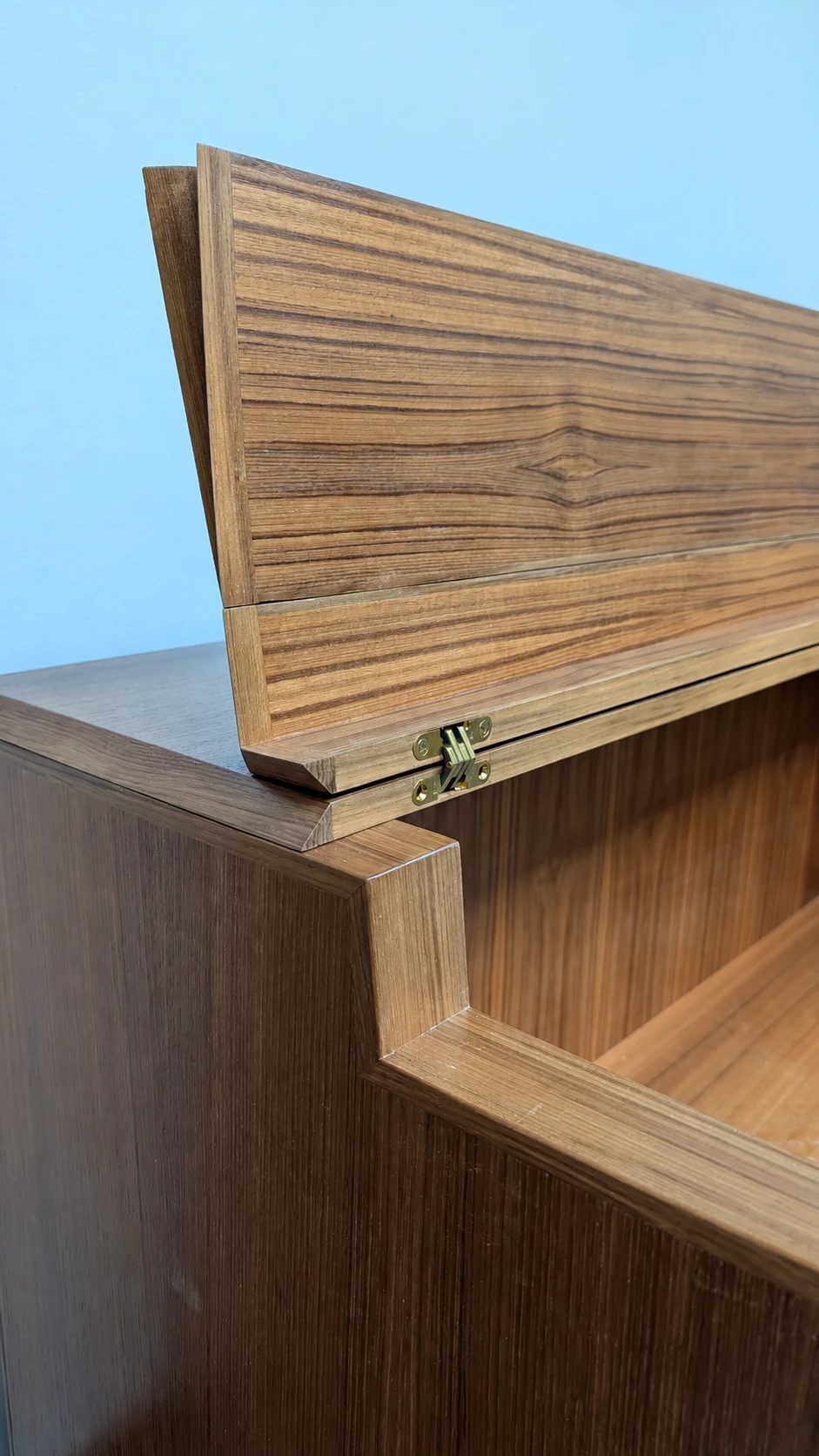 Close view of the teak lid’s angled edges and concealed hinge with the music stand unfolded.