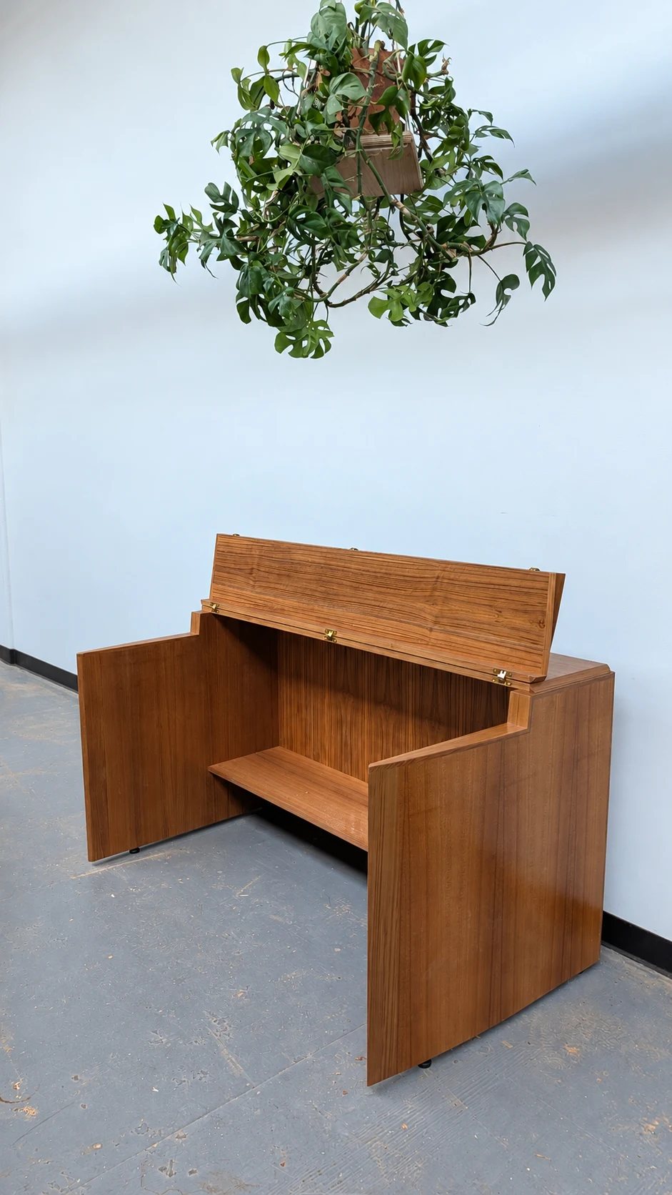 Teak keyboard stand with its lid folded up to form a music stand, showing the hinges and open keyboard space.