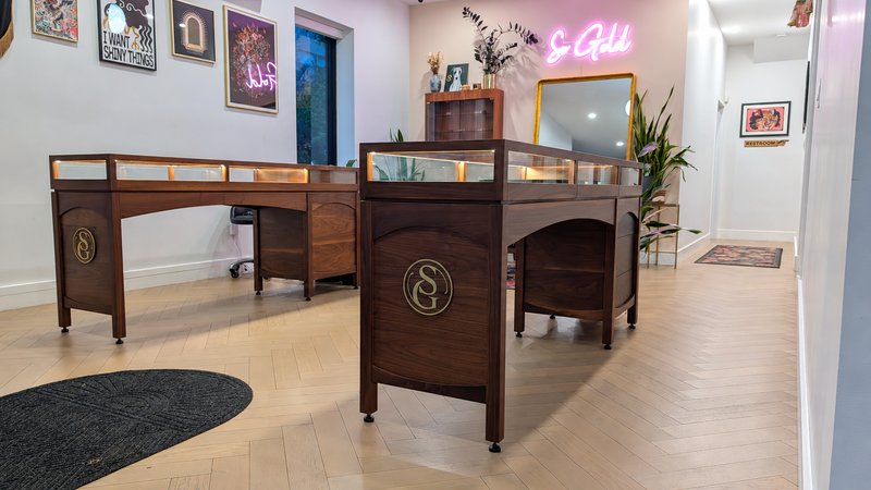 Display furniture with glass tops and curved openings at So Gold Studios.
