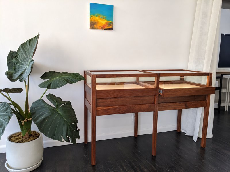 Walnut display case with the right upper drawer partially open and its drawer slide visible.