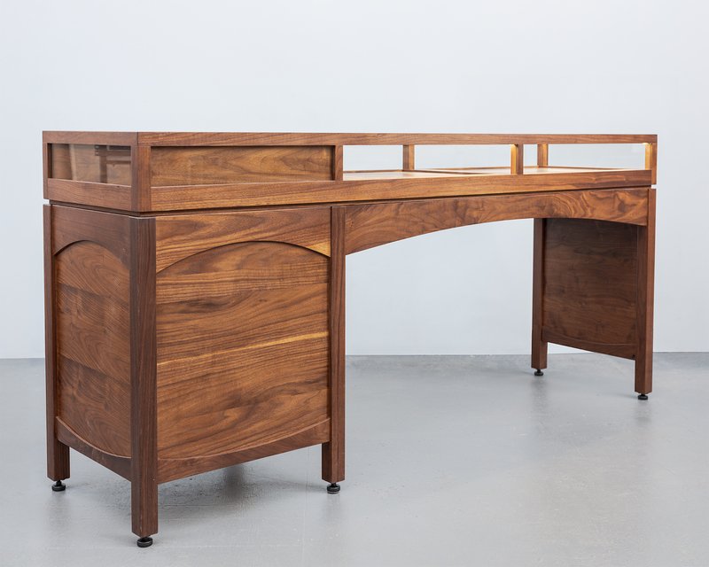 Wooden glass-topped display with curved panels, shown in a clear studio setting.